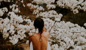 Donna con schiena nuda tra alberi in fiore